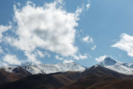 White cloud over the mountains. Blue sky and snowy mountains.の写真素材