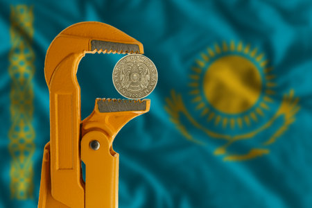 50 Kazakhstani tenge held in an orange plumber wrench on the background of the flag of Kazakhstan. Emblem of Kazakhstanの写真素材