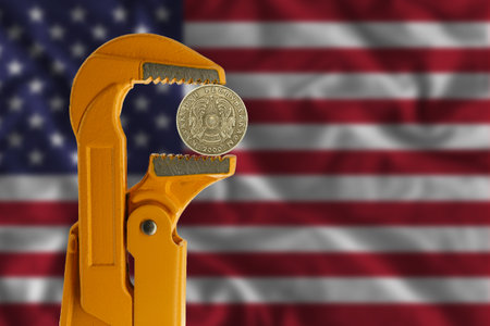 50 Kazakhstani tenge held in an orange plumber wrench on the background of the flag of the United States. Emblem of Kazakhstanの写真素材