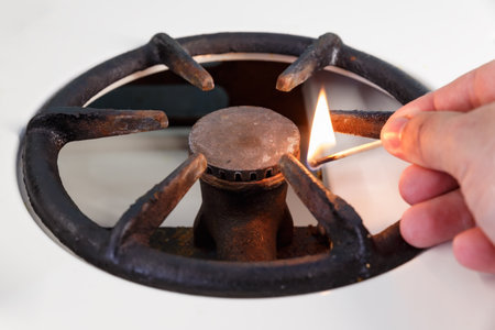 A man lights a gas stove with a match. vintage gas burner without flame. No gas.の写真素材