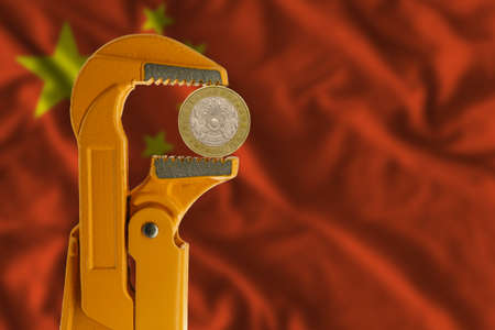 100 Kazakhstani tenge held in an orange plumber wrench on the background of the flag of China. obverse side of the coin.の写真素材