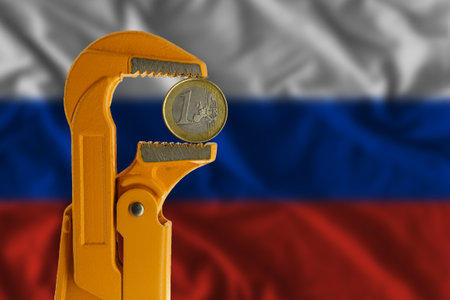 One euro coin held in an orange plumber wrench on the background of the Russian flag. reverse sideの写真素材