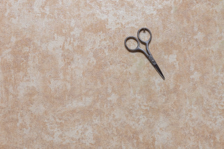 Manicure scissors hang on a small nail driven into the wall. Wall with wallpaper inside the house.の写真素材