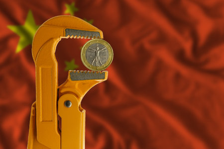 One euro coin clamped in an orange plumber wrench on the background of the flag of China. Obverse sideの写真素材