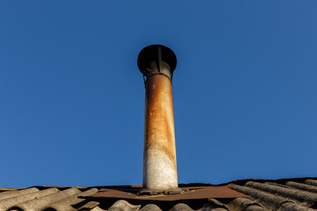 Chimney pipe on the roof of the house against the blue sky.の写真素材