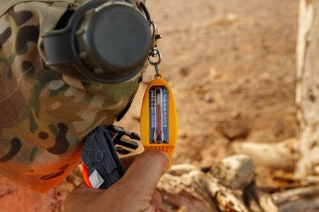 A man's hand holds a thermometer. The thermometer hangs on a flask of water. Measurement of air...