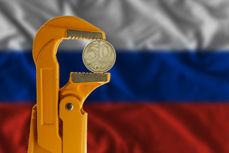 50 Kazakhstani tenge coin clamped in an orange plumber wrench on the background of the Russian flag. reverse side coinの写真素材