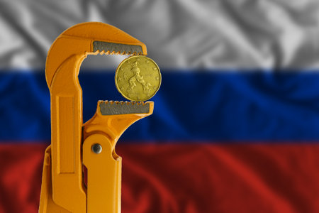 20 euro cent coin clamped in an orange plumber wrench on the background of the Russian flag. Obverse side coinの写真素材
