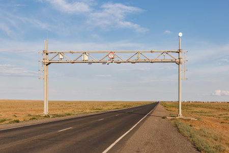 A road sign indicates speed limits above a long, open highway stretching through the expansive...