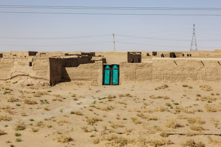 A traditional adobe house in Sheberghan features striking blue doors, surrounded by arid land under a clear sky, reflecting local architecture. Jowzjan Province, Afghanistanの写真素材