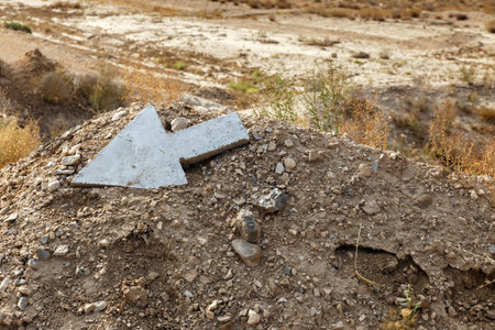 A concrete arrow marker directs travelers on the Gorgan Bojnord road in Iran, surrounded by dry terrain and sparse vegetation.の写真素材