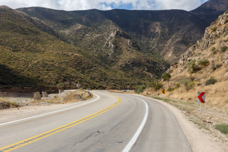 Curvy road leads through the mountainous terrain of Golestan National Park during daylight,...