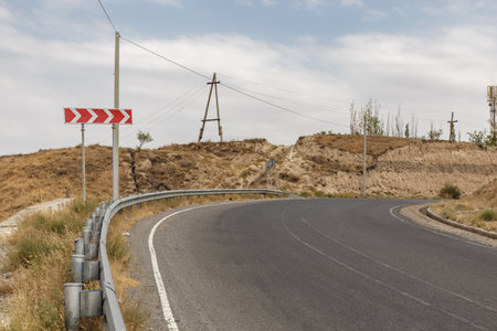 Winding road through arid landscape in Tajikistan during a cloudy dayの写真素材