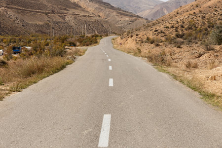 A winding road traverses a dry mountainous area in Iran, showcasing arid terrain and clear weather.の写真素材