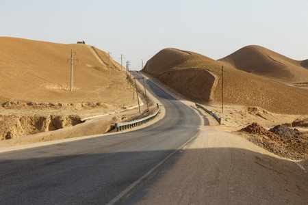 A long, winding road traverses the dry, sandy terrain of Faryab Province near Andkhoy and Maymana, showing the region's natural beauty. Afghanistanの写真素材