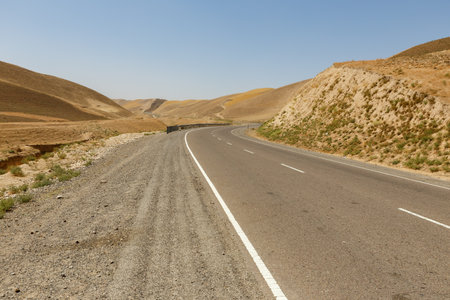 A winding road cuts through the dry, rugged terrain of Faryab Province, connecting Maymana and Qeysar. Afghanistanの写真素材