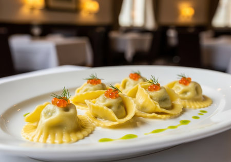 A gourmet appetizer of six ravioli pasta dumplings topped with red caviar and dill. The dish is served on a white plate in a fine dining restaurant.の素材