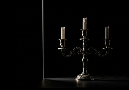 A vintage silver candelabra with unlit candles stands on a dark background, illuminated by a glowing vertical light line.の素材