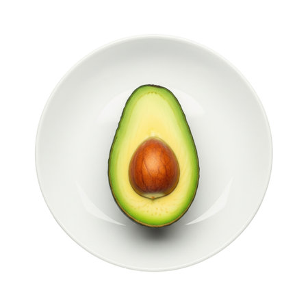 Half fresh ripe avocado with seed on white plate concept of healthy eating and diet food. A perfect ingredient for vegan breakfast.の素材