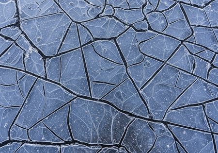 Abstract texture of cracked ice on a dark frozen surface creating a natural winter pattern. This cool background is beautifully broken.の素材
