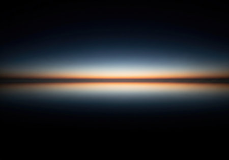 Minimalist abstract seascape at sunrise or sunset with a symmetrical reflection on calm water. A serene and peaceful nature background.の素材