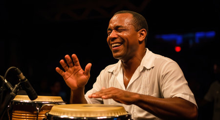 Happy African musician joyfully playing the conga drums during a live music performance on stage, smiling with passion and energy.の素材