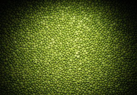 Texture background of dry split green peas with a dark vignette and a spotlight effect. A healthy vegetarian food ingredient top view.の素材