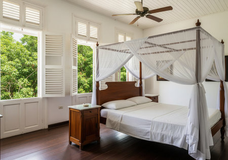 White colonial bedroom interior with four poster bed and open shutter windows to green nature, sunny historic house room design.の素材