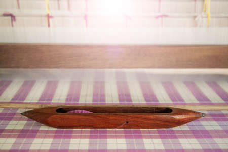 Wooden weaving shuttle on grid pattern hand woven cotton fabric.の写真素材