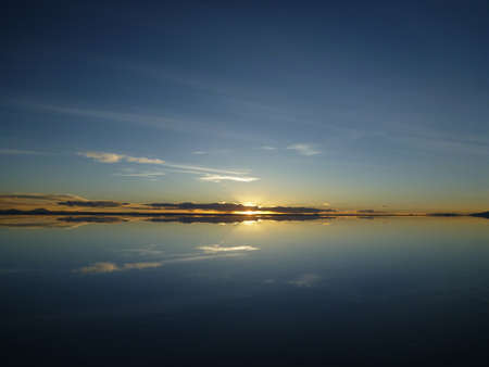 Sunrise reflected on the surface of the water like a mirror at Uyuni salt lake in Boliviaの写真素材