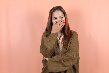 Beautiful Asian woman feeling happy and relaxed  isolated with peach backgroundの写真素材