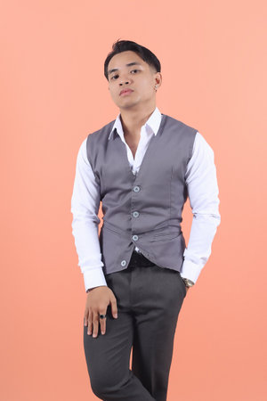 Handsome young Asian businessman wearing a suit vest with his left hand in his pocket confidently...