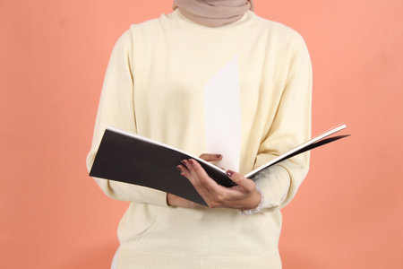 opening notebook and weiting something isolated over peach background smilingの写真素材