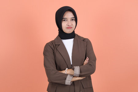 Business asian muslim woman cynical and angry keeping arms crossed and looking at camera wearing...