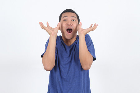 Surprised shocked face asian man looking up with raise hands isolated on white background for...