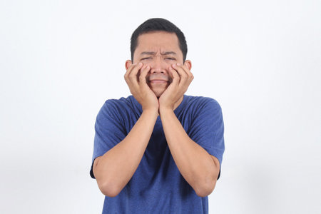 Scared asian guy shivering from fear and putting fingers nails on cheek, looking afraid and insecure at camera. Frightened man in panic stare anxious, witness terrible accident, watching horror movieの写真素材