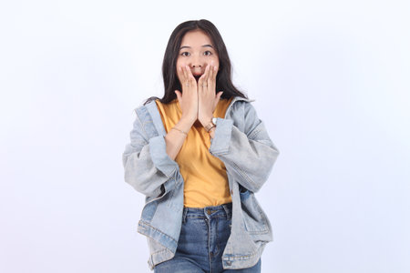 Shocked young Asian woman wearing blue jacket yellow t-shirt covering mouth and close mouth with hands expression face disgusting,  Isolated on white background.の写真素材