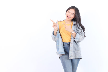 Beautiful young Asian woman pointing aside to copy space with smile face and happy Pretty girl act...