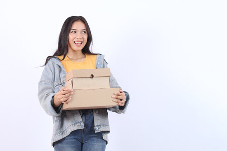 Happy Young Asian woman wearing blue jacket yellow t-shirt holding and giving package parcel boxes...