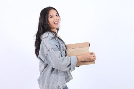 Happy Young Asian woman wearing blue jacket yellow t-shirt holding and giving package parcel boxes isolated on white background, Delivery courier and shipping service concept.の写真素材