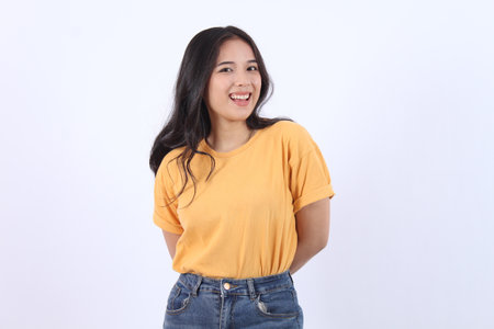 Cheerful Asian woman with confident smile looking at camera wearing yellow t-shirt isolated white backgroundの写真素材