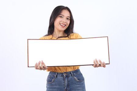 Beautiful young Asian woman on yellow t-shirt holding presentation book on white background. book...