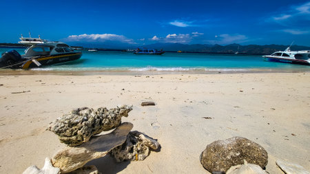 Tropical Beach Meets Boats Gently on White Sand with Coral Rocks Beautifullyの写真素材