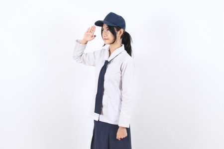 Asian high school girl wearing a traditional uniform and navy cap, standing with a serious look and...