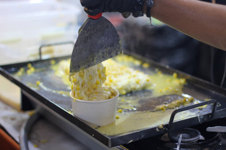 Cook serves a hot, gooey portion of delicious melted mozzarella cheese and sweetcorn into a cup. A...