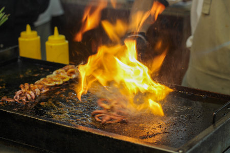 Professional chef flambeing fresh seafood with dramatic flames. Exciting culinary action at a...