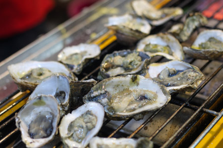 Close-up of delicious fresh oysters grilling on a hot barbecue. A gourmet seafood appetizer cooking...