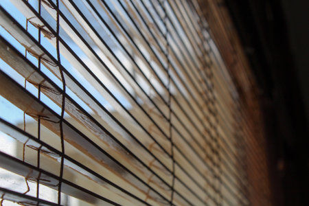 Close up view from inside a room looking through old venetian blinds at a bright, sunny day. Concept of hope, privacy, or quiet morning contemplation.の写真素材