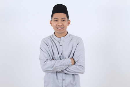 Portrait of a confident young Asian Muslim man in traditional attire smiling warmly. Perfect for Ramadan, Eid Mubarak, and cultural celebrations.の写真素材