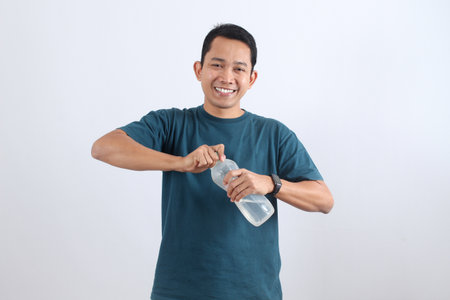 Cheerful Asian man opening a bottle of fresh water. Concept of hydration, refreshment, and a healthy active lifestyle.の写真素材
